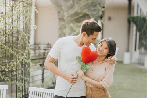 man and woman holding heart balloon