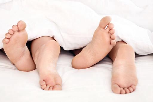 two pairs of feet under a cover