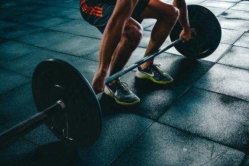 Mans arms in gym listing a dumbbell