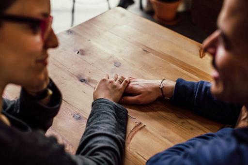 couple holding hands on table